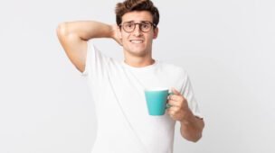 Rapaz com um copo de café na mão e cara de quem tomo muito café